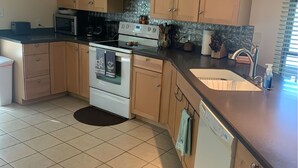 Une cuisine avec des meubles de rangement en bois, une cuisinière, un four à micro-ondes et un lave-vaisselle.