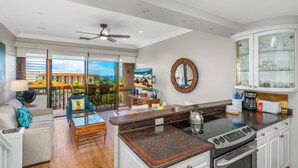 A modern kitchen with a large island, a dining area with a view, and a cozy living space with a sofa and coffee table. - Top Floor Maui Vista with Ocean View, AC, 5min Walk to Beach (Kihei)