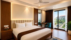 A modern hotel room with a large bed, a desk, a chair, a ceiling fan, and a view of the city. - Mystique Mayong  (Mayang)