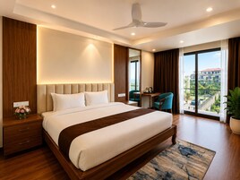 A modern hotel room with a large bed, a desk, a chair, a ceiling fan, and a view of the city.