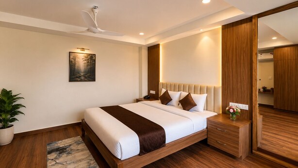 A modern bedroom with a wooden bed, a ceiling fan, a nightstand, a bedside table with a vase, and a large mirror. - Mystique Mayong  (Mayang)