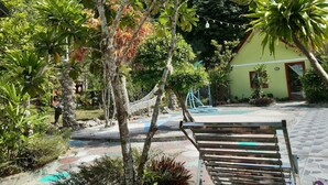 A pool area with a hammock, a bench, and a small building with a door. - CAT BA PARK HOMESTAY (Hai Phong)