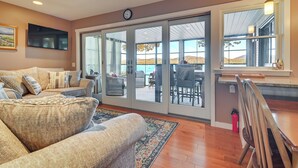 A living room with a sofa, a coffee table, and a rug. There is a sliding glass door leading to an outdoor patio area with a table and chairs. - Waterfront Lake Webb Cabin Rental w/ Dock & Views! (Weld)