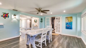 A dining area with a white table and chairs, a ceiling fan, and artwork on the walls. - Port Charlotte Home w/ Private Dock & Pool! (Port Charlotte)