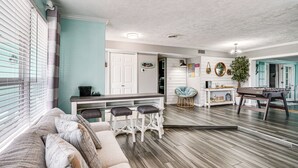 A modern living room with a sofa, bar stools, and a foosball table. - Port Charlotte Home w/ Private Dock & Pool! (Port Charlotte)