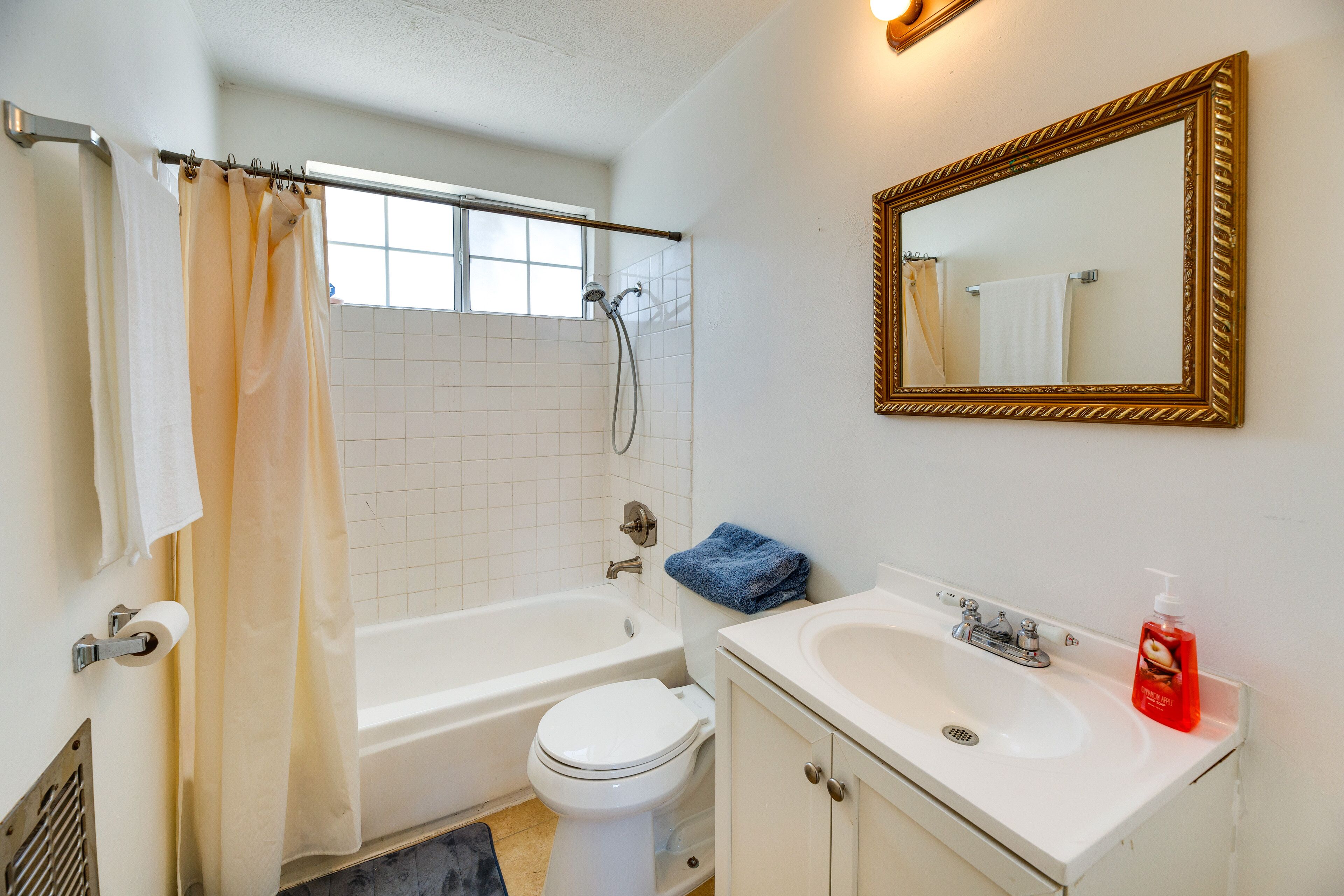 A bathroom with a bathtub, toilet, sink, and a mirror.