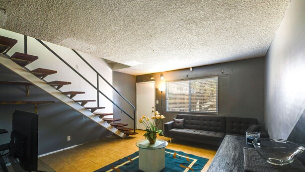 Een woonkamer met een trap, een bank, een salontafel en een televisie.