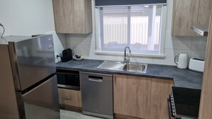 A modern kitchen with a stainless steel refrigerator, a dishwasher, a sink, and a window with a view. - Golden Heritage Accommodation Rutherglen (Rutherglen)