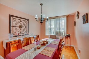 Comedor con una mesa de madera dispuesta para seis personas, una araña y un espejo decorativo grande en la pared.