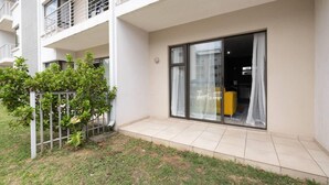A modern apartment with a balcony, large sliding glass doors, and a small garden area. - Sleeps4-pool-hottub-petfriendly-garden (Johannesburg)