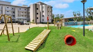 A playground with a wooden slide, a red tunnel, and a climbing structure. - Sleeps4-pool-hottub-petfriendly-garden (Johannesburg)