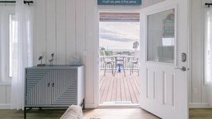Ein Zimmer mit einer weißen Tür, die auf eine Terrasse mit Blick auf den Strand führt.