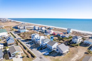 An aerial view of a coastal residential area with houses, a beach, and a clear sky.
