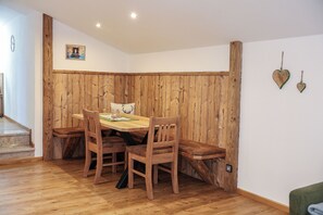 Un coin repas avec une table et des chaises en bois, un banc et un mur décoratif en bois.