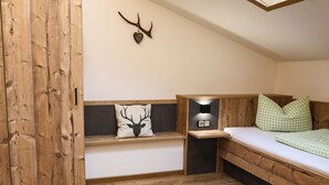 A cozy room with a wooden bed, a bench with a deer pillow, and a mounted deer head on the wall.