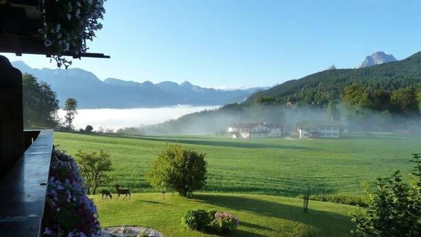 A serene landscape with a view of mountains and a misty lake.