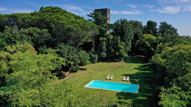 A swimming pool surrounded by lush greenery and a tower structure in the background. - Torre delle Cornacchie (Rome)