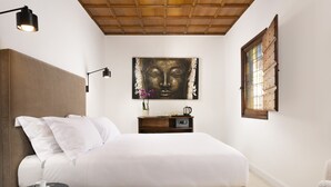 A bedroom with a large bed, a bedside table, a lamp, a wall-mounted artwork, and a window with wooden shutters. - Torre delle Cornacchie (Rome)
