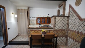 A compact kitchen with a tiled backsplash, a wooden countertop, and a dining area with a bench. - 1 Bedroom Apartment in Catania (Catania)
