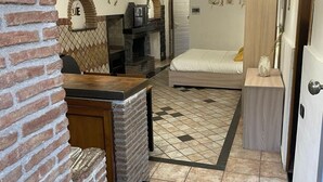 A compact living space with a kitchen area, a fireplace, a bed, and a small table. - 1 Bedroom Apartment in Catania (Catania)