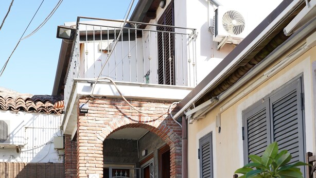 A residential building with a brick archway entrance, potted plants, and a tiled walkway. - 1 Bedroom Apartment in Catania (Catania)