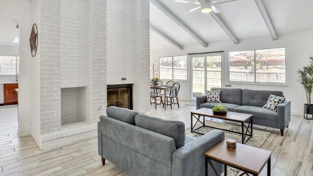 A spacious living area with a fireplace, grey sofas, a dining table, and large windows. - San Antonio Escape. Close to Lackland, SeaWorld, Fiesta Texas, and Riverwalk (San Antonio)