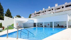 A swimming pool with a clear blue water, surrounded by a white building with balconies. - La Cala townhouse, beach 400 m, roof terrace, BBQ (La Cala de Mijas)