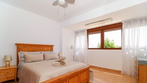 A bedroom with a wooden bed, a nightstand, a window with curtains, and a ceiling fan. - La Cala townhouse, beach 400 m, roof terrace, BBQ (La Cala de Mijas)