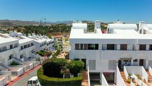 A modern building with white exterior walls, multiple balconies, and a well-maintained garden area. - La Cala townhouse, beach 400 m, roof terrace, BBQ (La Cala de Mijas)