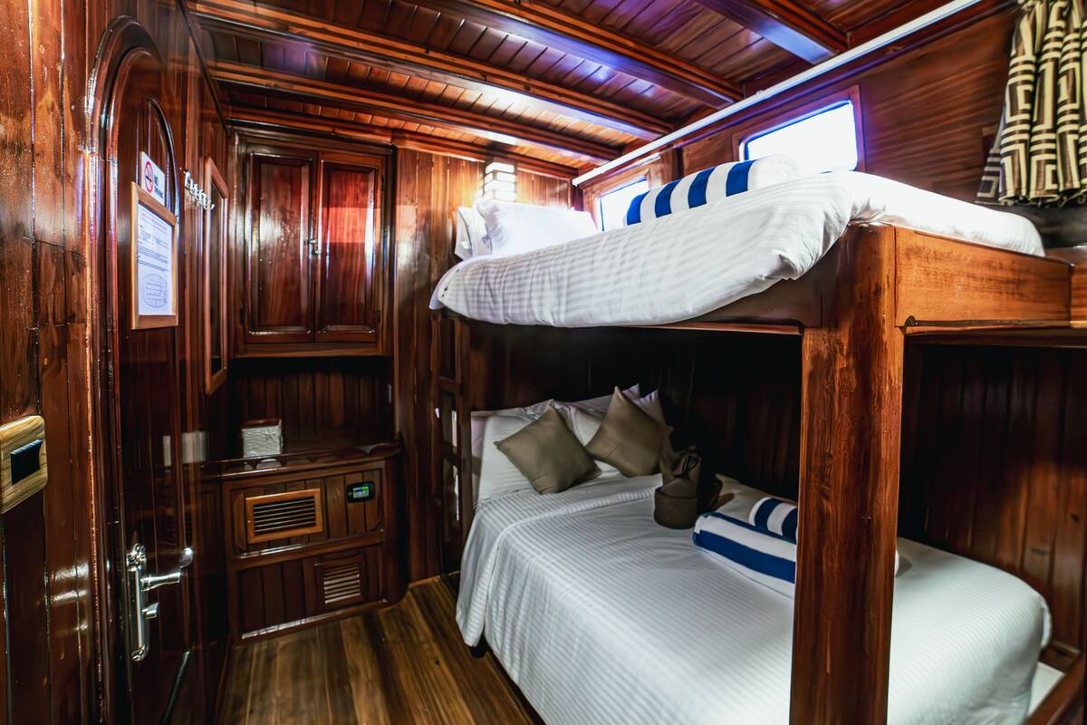 L’intérieur d’une cabane en bois, avec un lit superposé, des armoires en bois et un petit bureau.