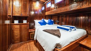 Un dormitorio tipo cabaña de madera con una cama grande, dos ventanas y armarios empotrados de madera.