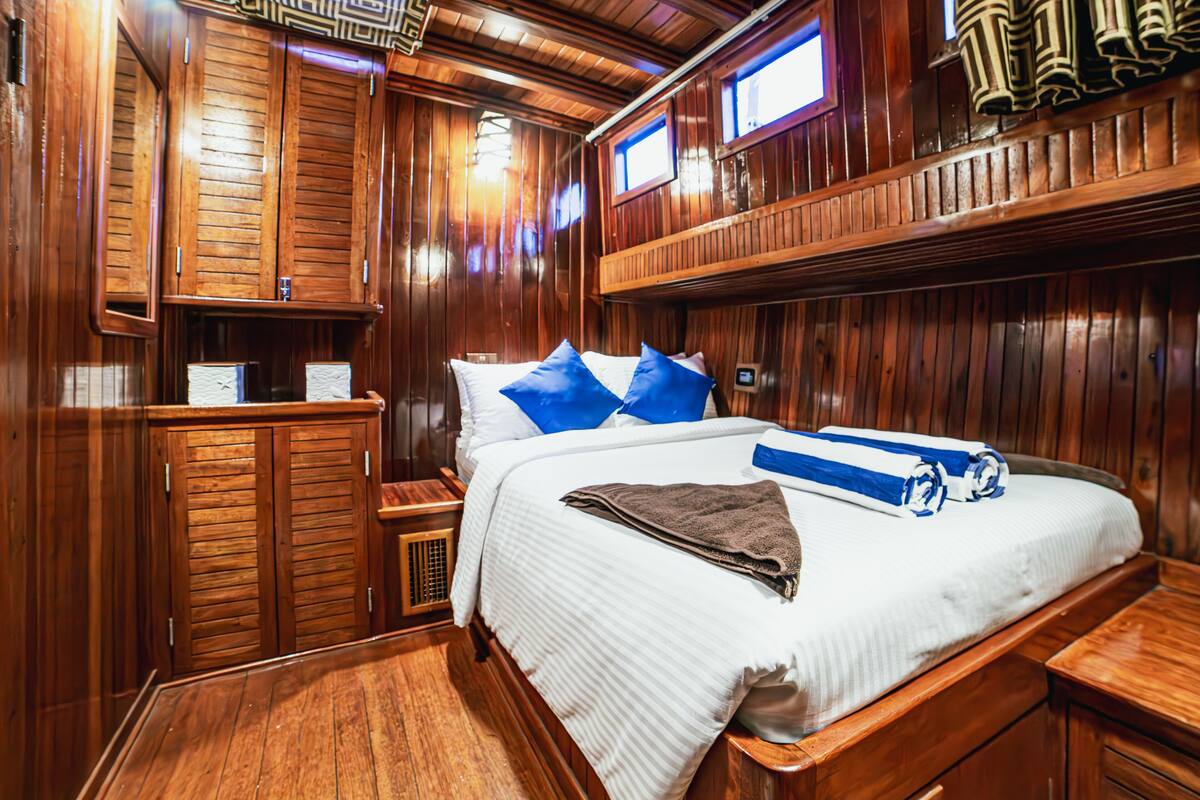 Une chambre de style cabane en bois, dotée d’un grand lit, de deux fenêtres et d’armoires encastrées en bois.