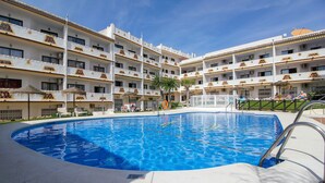 Una piscina de 90 metros de largo, rodeada por un hotel de varios pisos con balcones y mobiliario exterior.