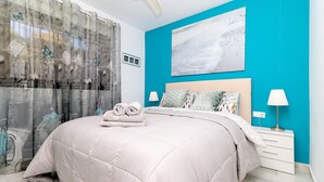 Un dormitorio con cama, mesita de noche, lámpara, ventana con cortinas y un cuadro en la pared.
