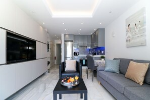 Un espace de vie moderne comprenant un canapé, une table à manger et une cuisine en arrière-plan.