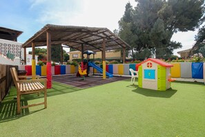 Un área de juegos infantiles con un tobogán, una casita y un banco.