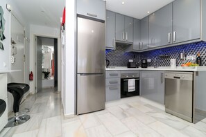 Una cocina moderna con electrodomésticos de acero inoxidable, gabinetes grises y salpicadero de azulejos.