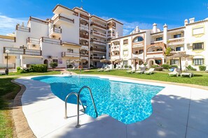 Un hotel con piscina, varios balcones y un césped cuidado.