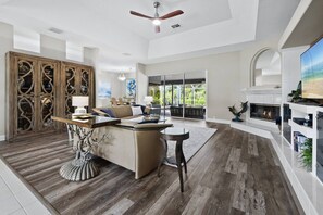 A spacious living area with a fireplace, a large TV, and a dining area with a tree-themed table.