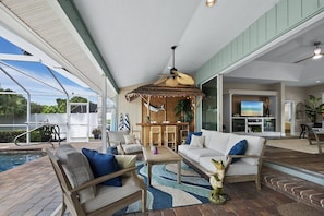 A spacious indoor area with a pool, seating, and a bar area. - Luxury Canal Home | Pool, Spa & Dock Near Beach (Nokomis)
