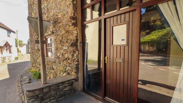 Un bâtiment en pierre avec une porte en bois et une fenêtre.