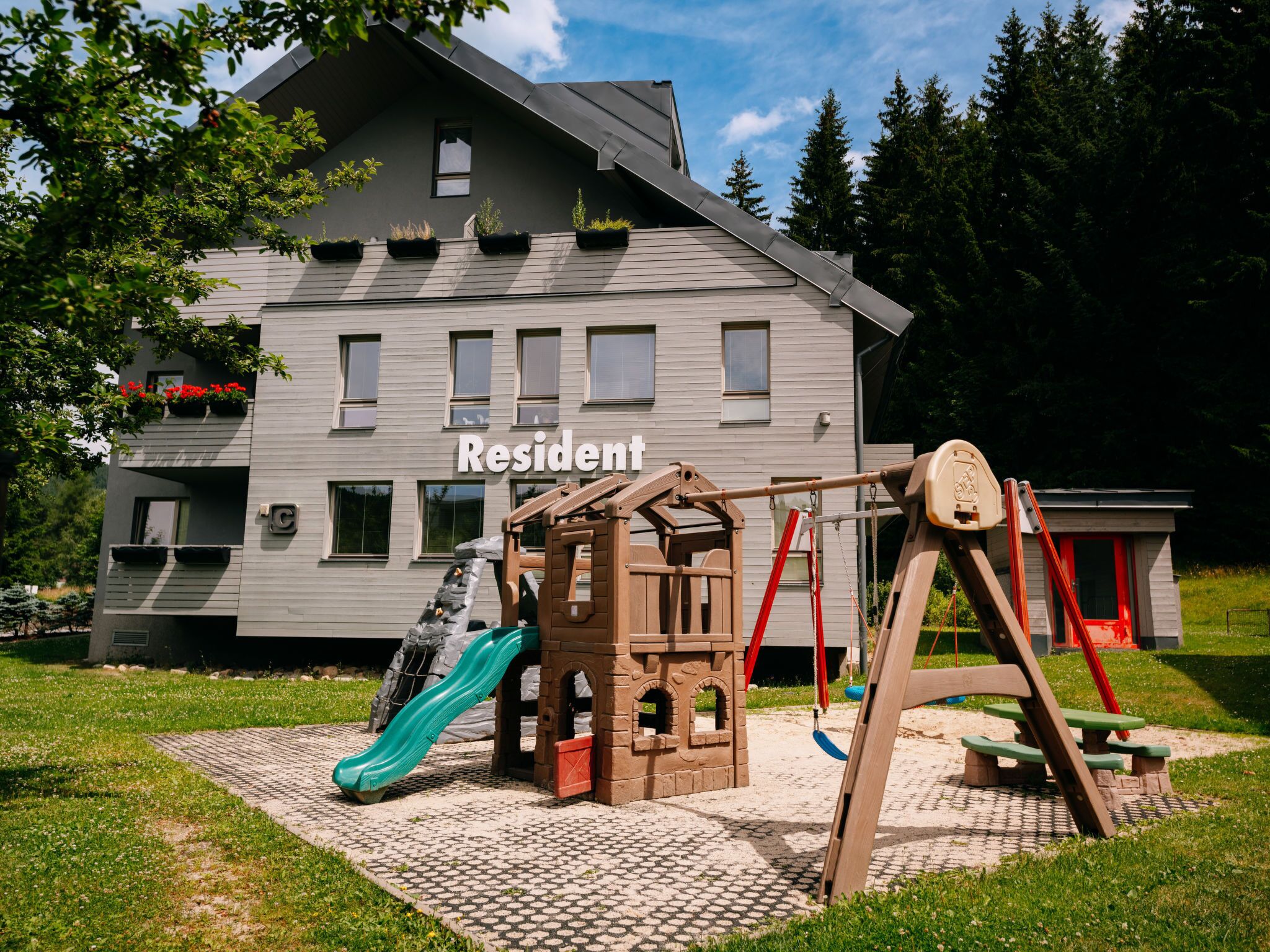 A playground with a slide and swings in front of a building labeled "Resident".
