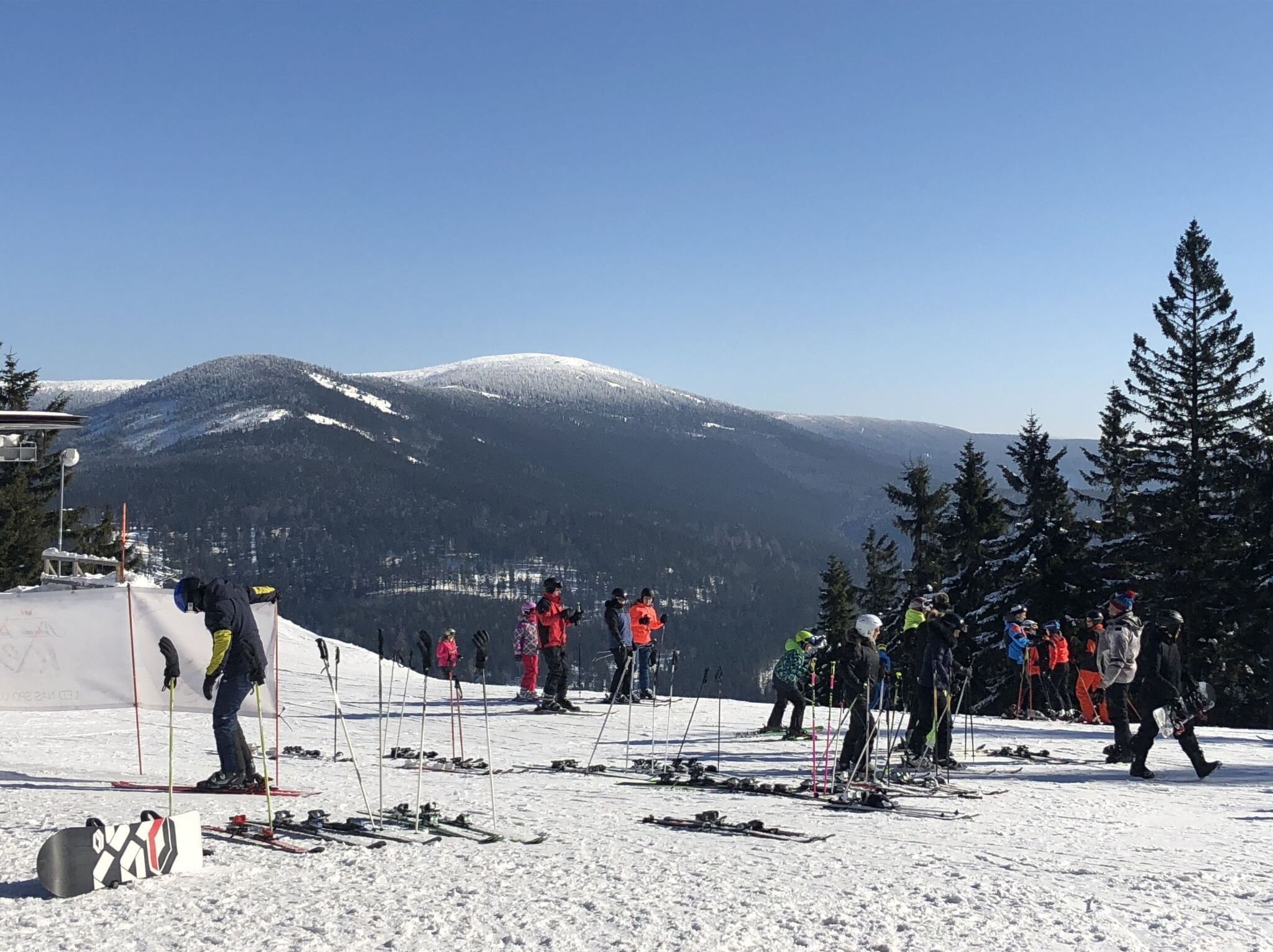 A ski slope with skiers and snowboarders preparing for their runs.