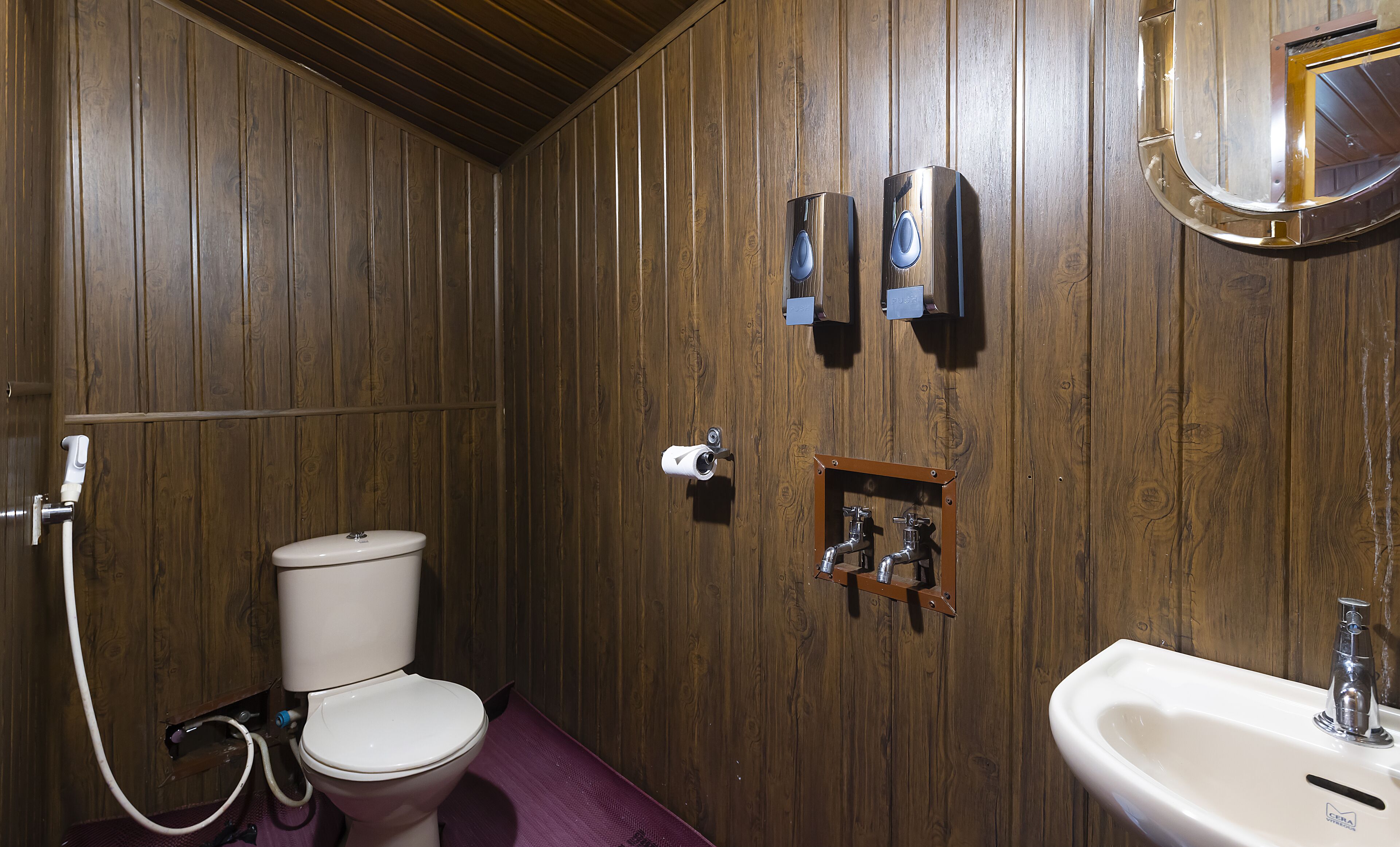 A wooden-paneled bathroom with a toilet, bidet, and sink.
