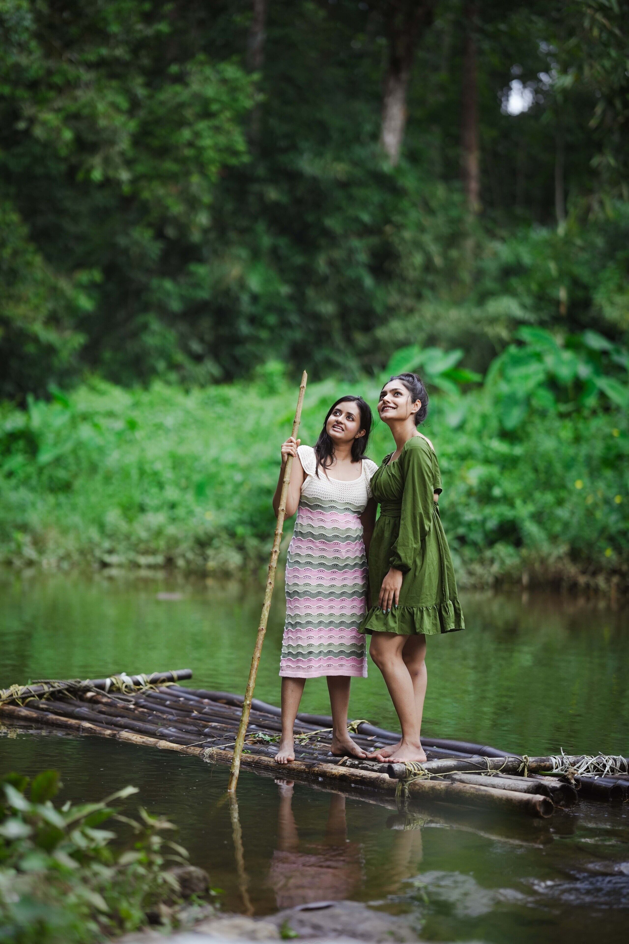 Dos personas en una balsa de bambú en un río rodeado de abundante vegetación.