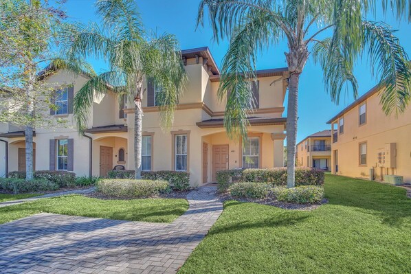 A residential building with a paved driveway, well-maintained lawn, and palm trees. - Family Resort Close To Disney (Davenport)