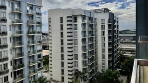 Um edifício residencial alto com várias varandas, uma garagem de estacionamento e vista para uma autoestrada.