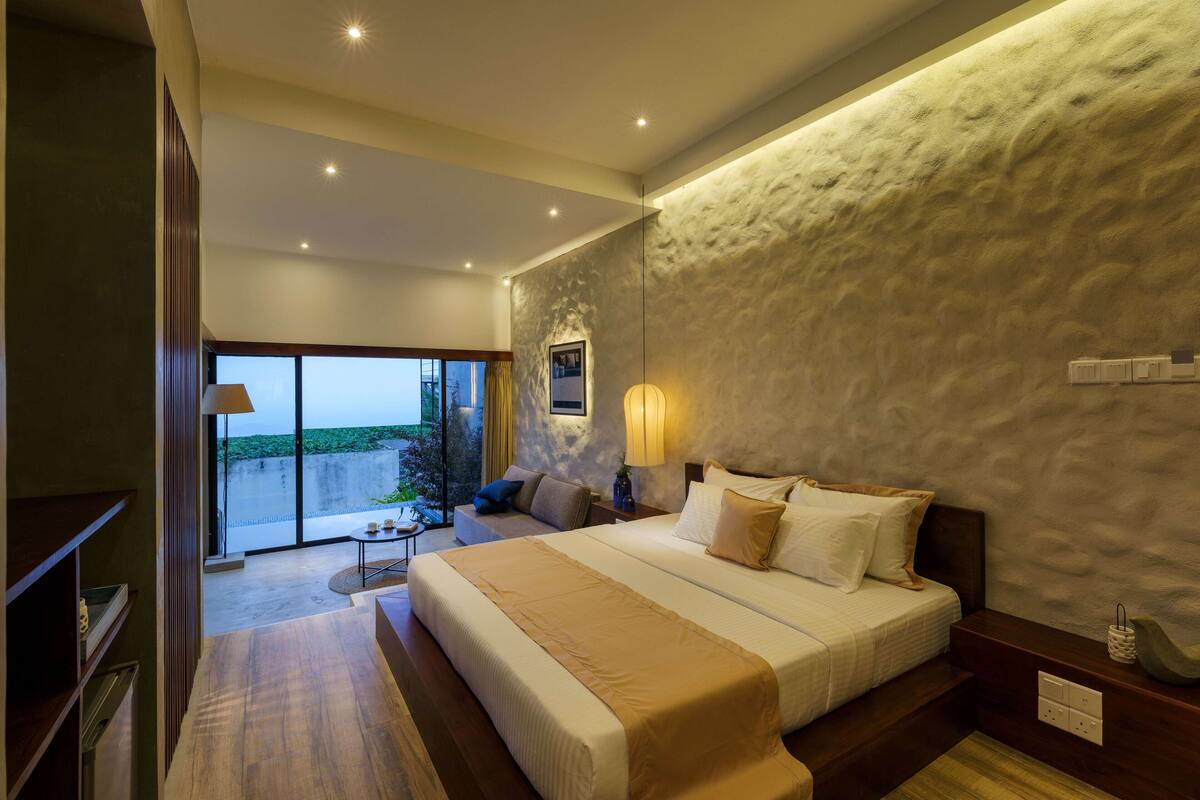 Ein modernes Hotelzimmer mit einem großen Bett, einer Sitzecke mit Aussicht und einem Balkon.