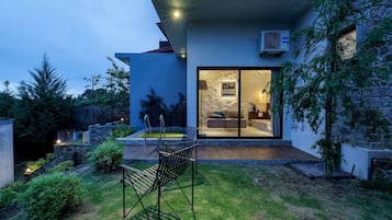 Uma casa moderna com porta de vidro que dá para uma sala de estar, piscina e jardim bem cuidado.