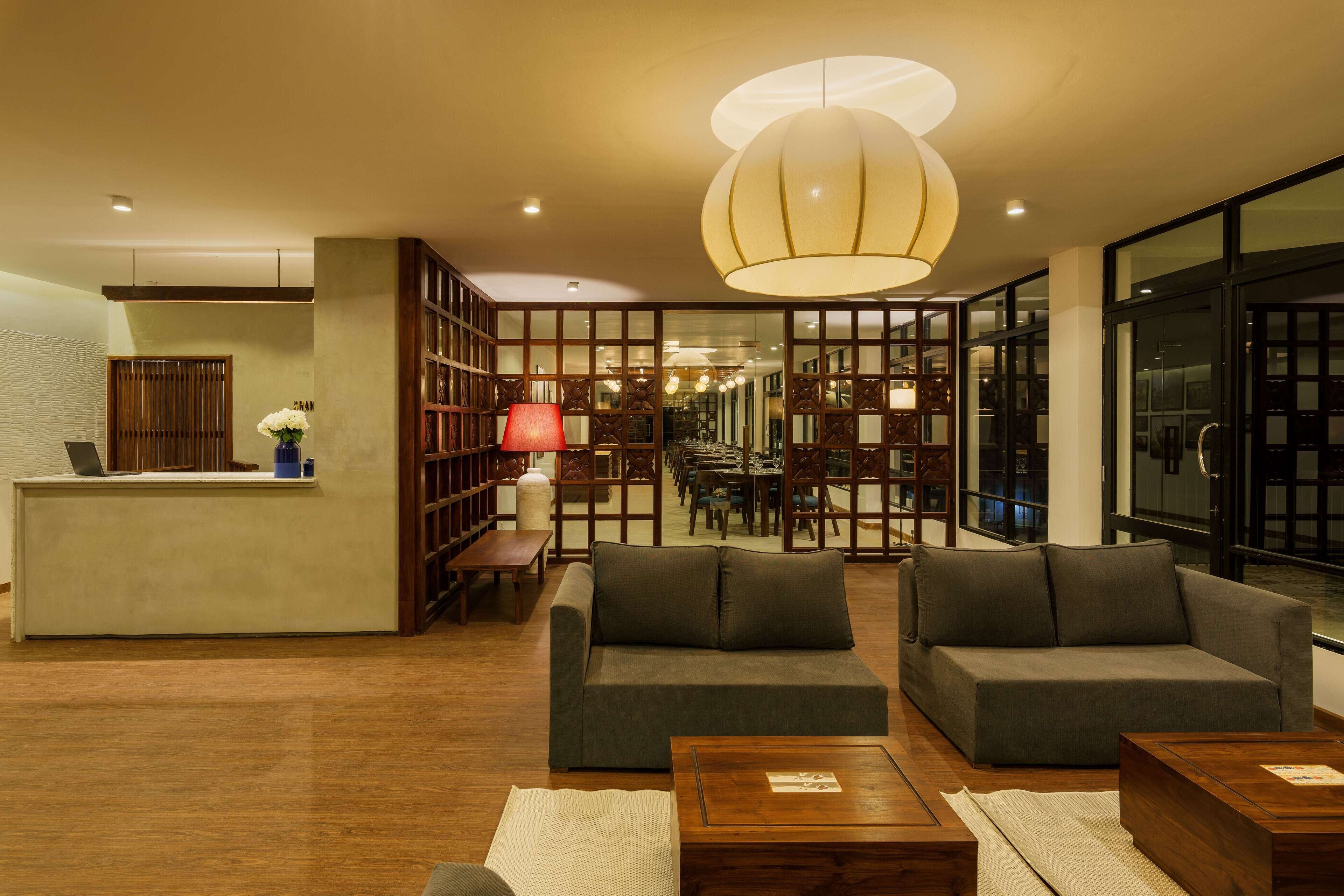 A modern lobby with a reception desk, seating area, and a view of the dining area.